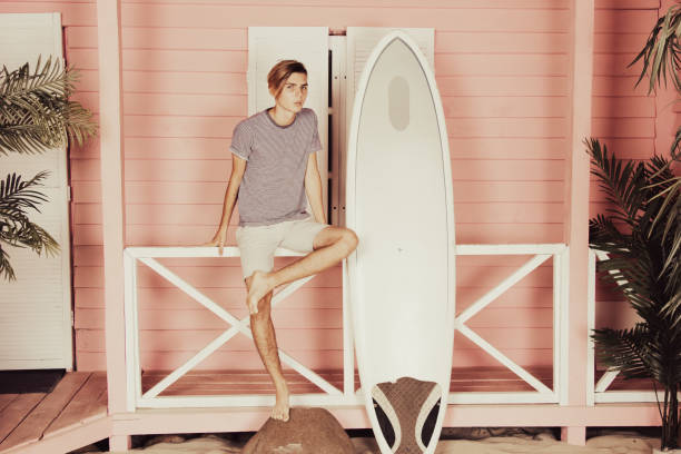istock Vacation at sea. Young attractive guy on the beach with a surfboard. 2178677169