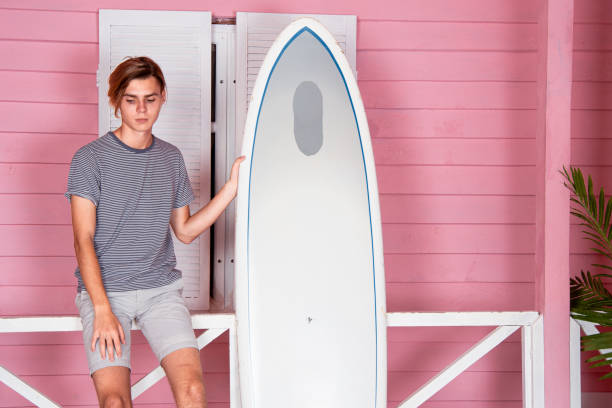 istock Vacation at sea. Young attractive guy on the beach with a surfboard. 2178678031