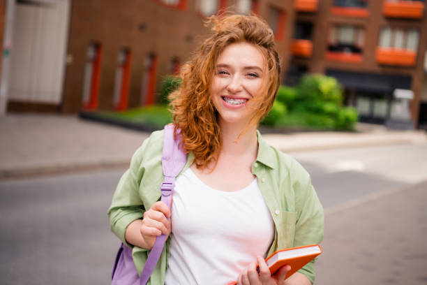 istock Young redhaired student enjoying a sunny day outdoors, smiling with books in hand during a relaxed weekend stroll 2178678338
