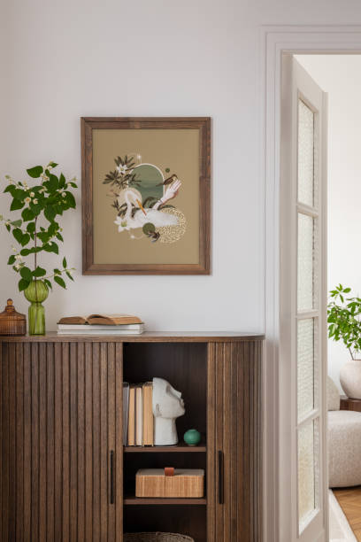 istock Stylish interior with a wooden cabinet adorned with potted plants, decorative objects, and books. A vibrant art piece featuring a sunburst design adds a pop of color. Cozy seating area visible in the background. 2178680336