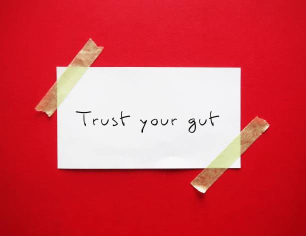 istock Note stick on red background with handwritten text TRUST YOUR GUT refers to trusting feelings of intuition. Following  instinct, can be valuable tool in some circumstances 2178682519