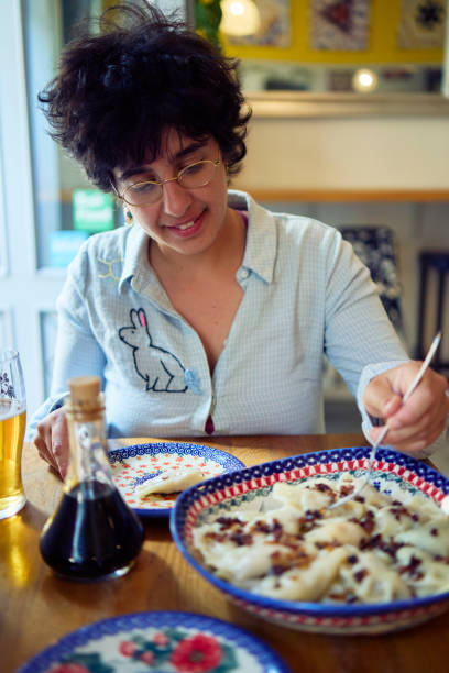 a young plus size woman eating pierogi in a restaurant