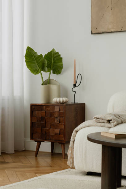 istock A stylish, minimalist living room area featuring a mid-century modern commode with a cozy decorations, leafs in vase. The room includes elegant decor, soft lighting, and a tranquil ambiance. 2178684572