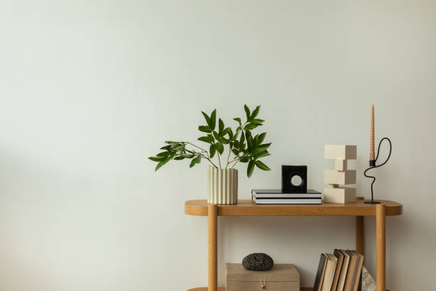 istock A minimalist interior featuring a wooden shelf with stylish decor items, including a green plant in a ribbed vase, modern sculptures, books, and a unique candle holder. The setup exudes simplicity and elegance. 2178686565