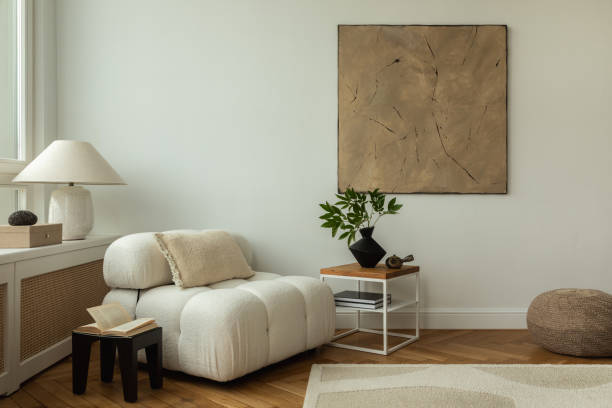 istock A modern living room interior featuring cozy, plush white sofas a wooden side table with decorative items, and minimalist decor. The space is enhanced by a large abstract painting and a soft rug, creating a warm, inviting atmosphere. 2178686585