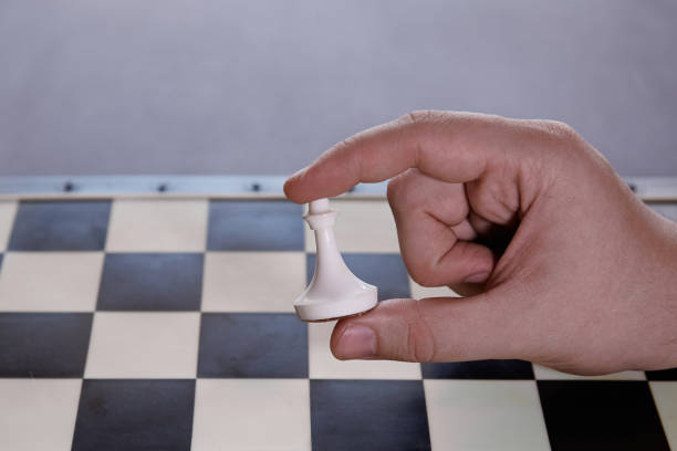 istock A white pawn in a person's hand before an empty chessboard, choice, beginning of a journey, ambitions, vulnerability and potential for growth, importance of first steps 2178687184