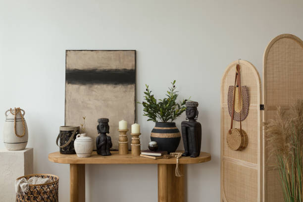 istock Modern living room interior with a minimalist design. Features a wooden table adorned with decorative vases and sculptures, a wooden chair with a woven seat, and a large abstract painting on the wall. Natural light highlights the calm and cozy atmosphere. 2178689901