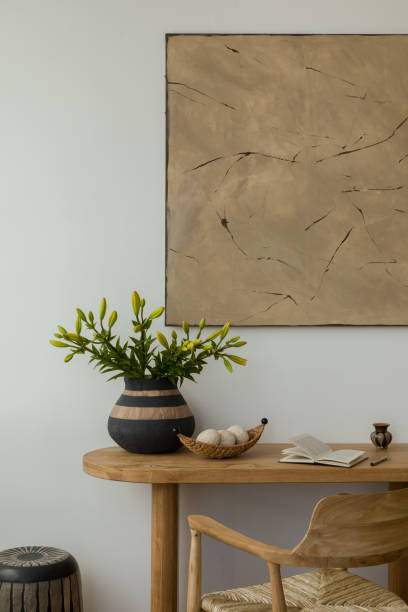 istock Aesthetic interior design featuring a wooden console table and chair  adorned with decorative vases, candles, and  sculptures. A large abstract painting adds a modern touch. Stylish space. Template. 2178689915