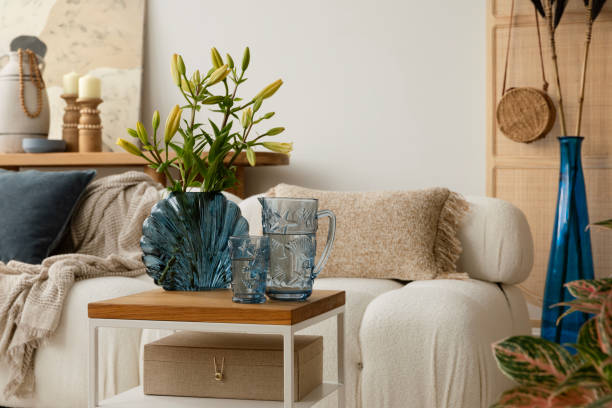 istock Cozy and boho  living room featuring a white sofa with textured cushions and blankets, a wooden coffee table with decorations, and decorative elements in natural tones. Stylish home interior. Template. 2178689929