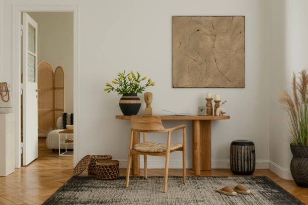 istock Modern living room interior with a minimalist design. Features a wooden table adorned with decorative vases and sculptures, a wooden chair with a woven seat, and a large abstract painting on the wall. Natural light highlights the calm and cozy atmosphere. 2178689966