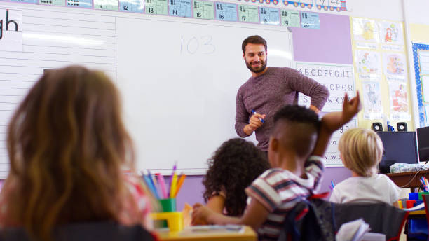 istock Male Teacher Standing At Whiteboard Teaching Maths Lesson To Elementary Pupils In School Classroom 2178694679
