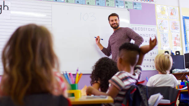 istock Male Teacher Standing At Whiteboard Teaching Maths Lesson To Elementary Pupils In School Classroom 2178694823