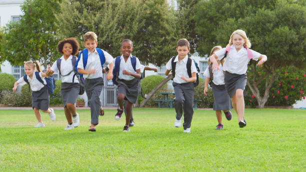 istock Excited Elementary School Pupils Wearing Uniform Running Across Field At Break Or Going Home Time 2178695029
