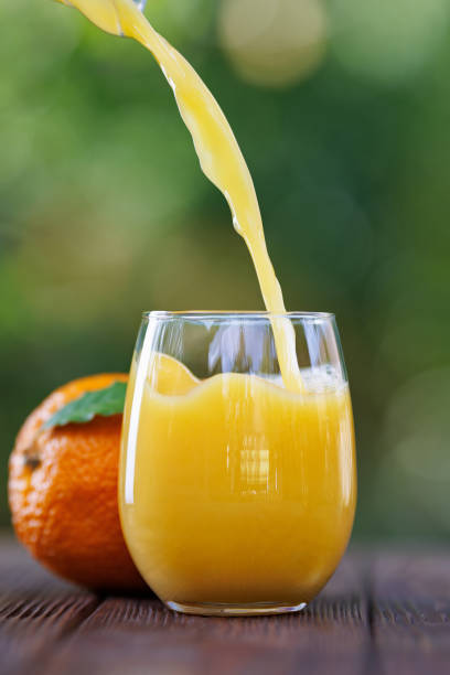 istock orange juice pouring into glass on table outdoors 2178695797