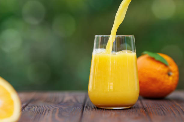 istock orange juice pouring into glass on table outdoors 2178695802