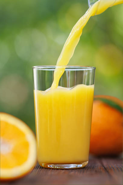 istock orange juice pouring into glass on table outdoors 2178695807