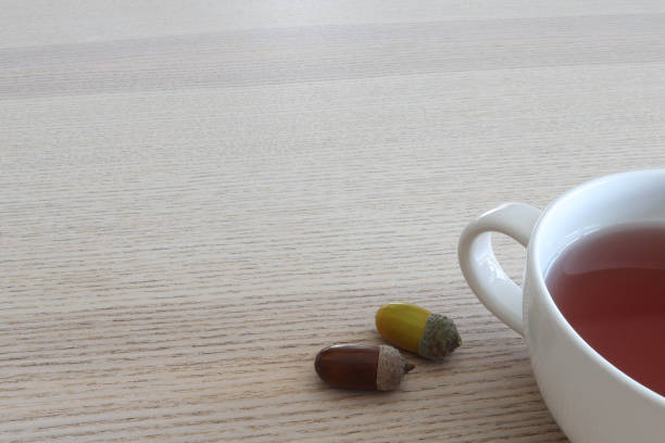 Cup of tea on wooden table, with two color acorns