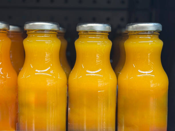 The image showcases an organized collection of glass bottles that appear to be filled with yellowish-orange\nliquid, suggesting they are mockups for fresh fruit juice.