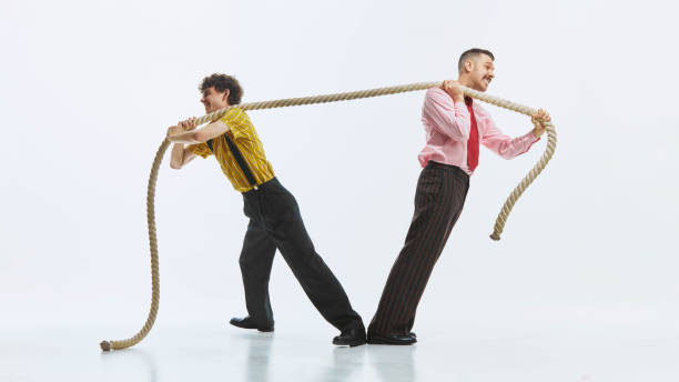 istock Two men engaged in tug of war, one pulling rope with all his strength while other in resistance, showing competitive spirit. 2178698976