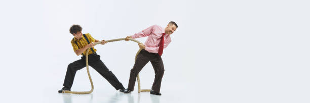 istock Two men engaged in tug of war, one pulling rope with all his strength while other in resistance, showing competitive spirit. 2178698985