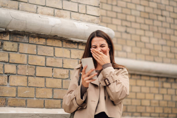 istock Young woman is laughing while reading a message on her smartphone 2178700003