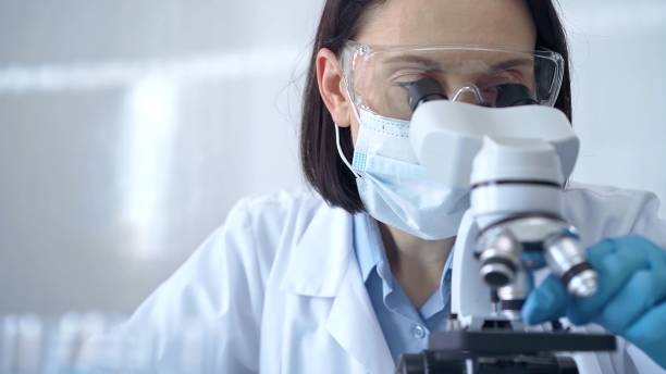 istock Female scientist in lab goggles, protective mask and gloves is using microscope in laboratory. Science concept 2178702430