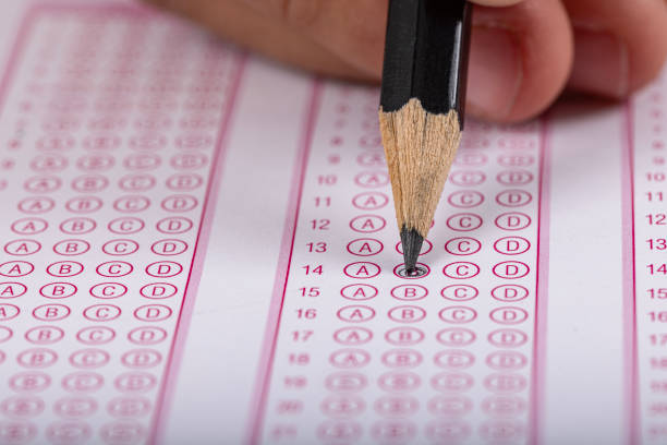 istock Exam, a hand taking an exam with a pen on an optical reader. Exam, an idea concept. Anxiety about the future, uncertainty. Multiple choice exam. Adults taking an exam. 2178702737