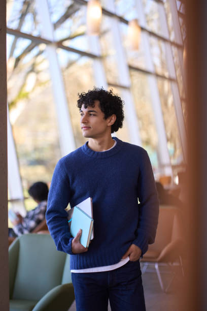 istock Thoughtful university student holding books in modern library building 2178702838