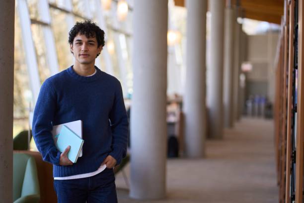 istock Confident university student holding books in library corridor 2178702845