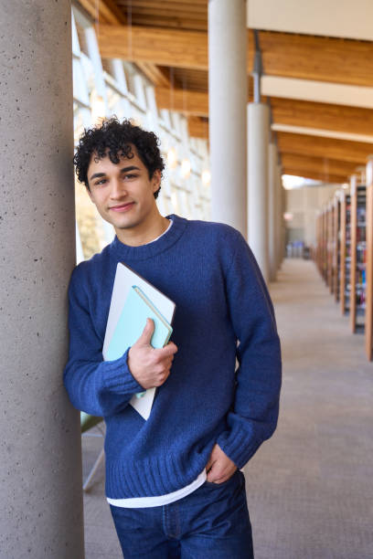 istock Young student holding books and smiling in library 2178702853
