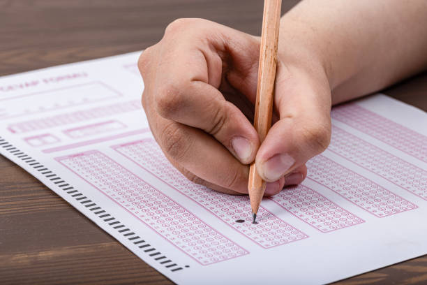 istock Exam, a hand taking an exam with a pen on an optical reader. Exam, an idea concept. Anxiety about the future, uncertainty. Multiple choice exam. Adults taking an exam. 2178702874