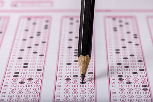 istock Exam, a hand taking an exam with a pen on an optical reader. Exam, an idea concept. Anxiety about the future, uncertainty. Multiple choice exam. Adults taking an exam. 2178702912