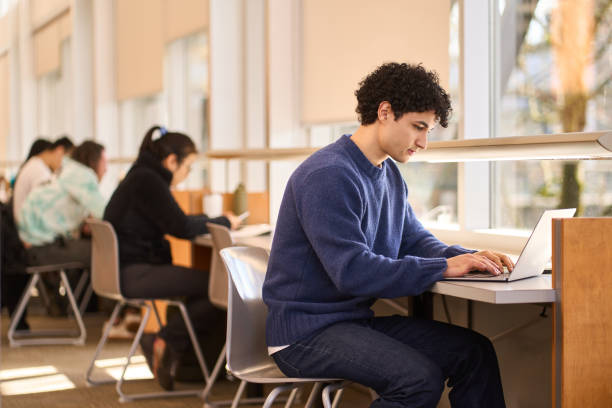 istock Focused student working on laptop in busy college library 2178702925