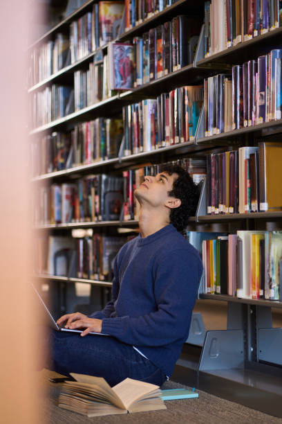 istock Thoughtful student contemplating choosing a book in the library 2178702926