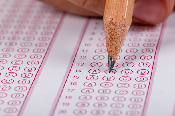 istock Exam, a hand taking an exam with a pen on an optical reader. Exam, an idea concept. Anxiety about the future, uncertainty. Multiple choice exam. Adults taking an exam. 2178703068