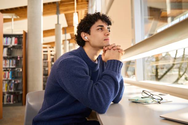 istock Pensive student listening to podcast and thinking in university library 2178703086