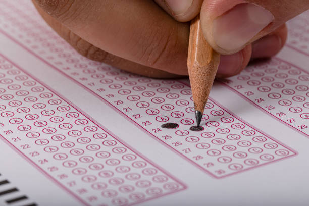 Exam, a hand taking an exam with a pen on an optical reader. Exam, an idea concept. Anxiety about the future, uncertainty. Multiple choice exam. Adults taking an exam.