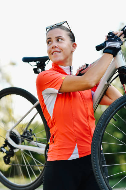 istock Confident Female Biker Carrying Bike on Shoulder Looking Sideway When Seeing Friend Approaching 2178703528