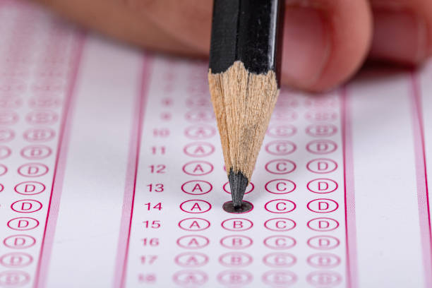 istock Exam, a hand taking an exam with a pen on an optical reader. Exam, an idea concept. Anxiety about the future, uncertainty. Multiple choice exam. Adults taking an exam. 2178704088