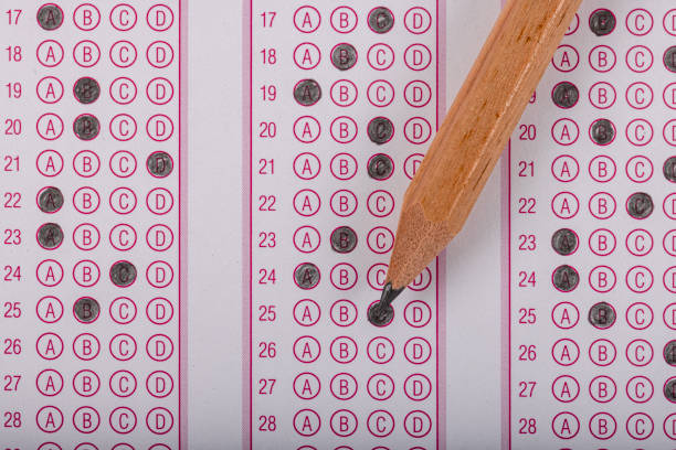istock Exam, a hand taking an exam with a pen on an optical reader. Exam, an idea concept. Anxiety about the future, uncertainty. Multiple choice exam. Adults taking an exam. 2178704463