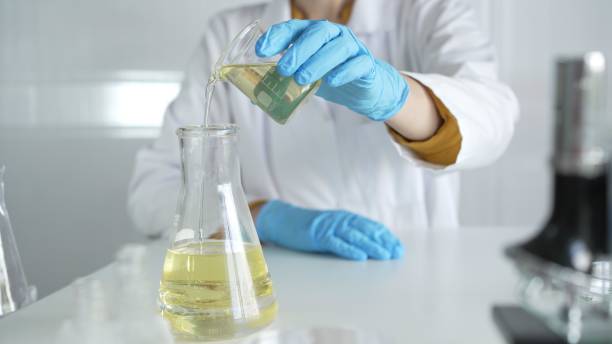 istock A scientist, wearing a lab coat and blue protective gloves, is pouring a yellow liquid from one beaker to another in laboratory, close up. Medicine and science concepts 2178705837