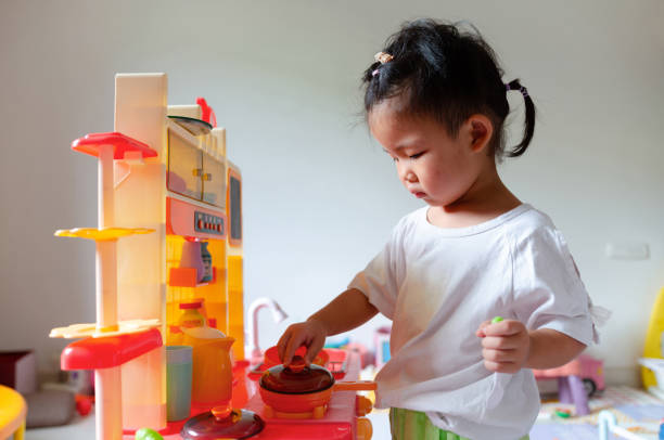 A child is cooking in the toy kitchen