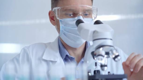 istock Man scientist with protective glasses, mask and gloves is using microscope in laboratory, portrait of researcher. Microbiology science concept 2178721522