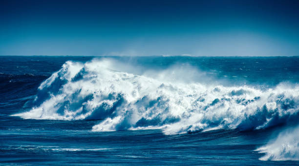 istock Powerful ocean waves crash along a rocky shore under a clear blue sky at midday 2178728722