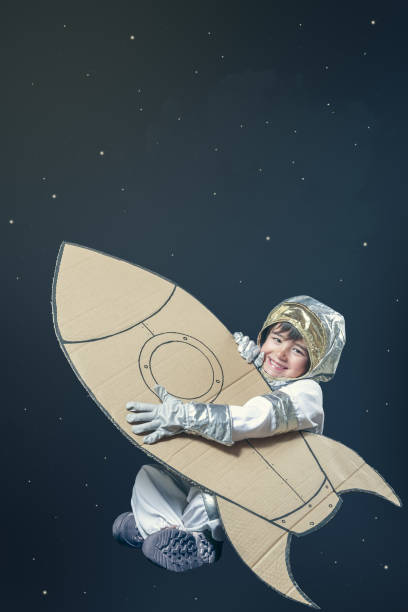 istock A smiling boy is dressed in a space suit and holding a cardboard rocket. 2178741722