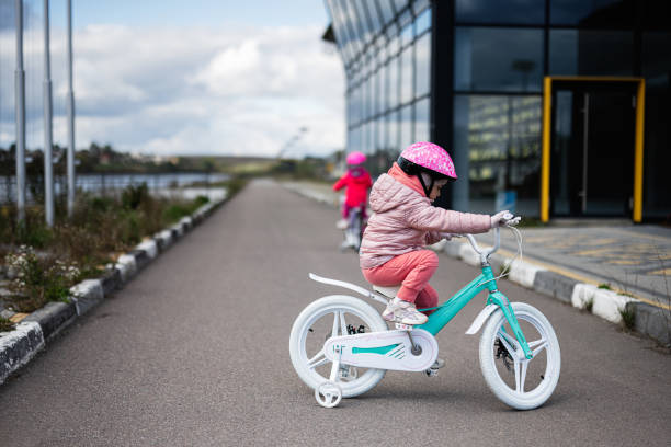 istock Young Girl Riding Bicycle with Training Wheels Outdoors 2178742214