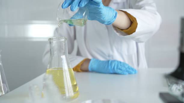istock A scientist, wearing a lab coat and blue protective gloves, is pouring a yellow liquid from one beaker to another in laboratory, close up. Medicine and science concepts 2178745091