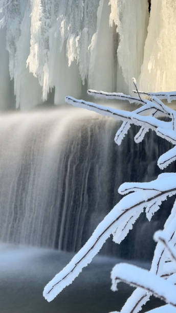 istock Frozen waterfall in winter, tree branches covered in white fluffy snow, mobile phone photo 2178746207