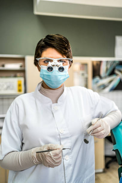 Young female dentist with microscope glasses and dental equipment tools in dental office