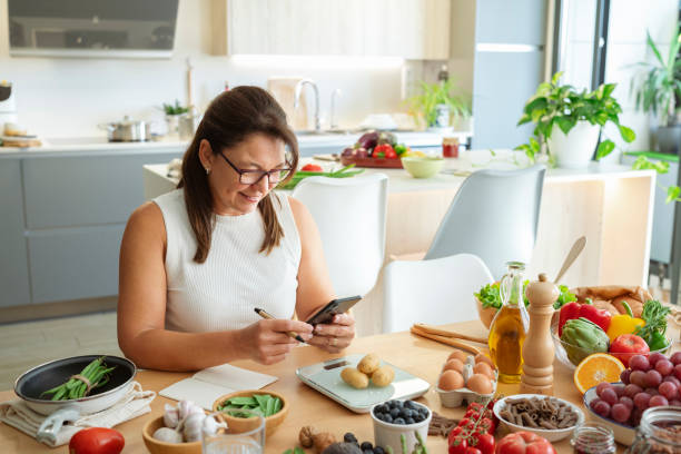istock Nutritious Choices After 50: Balanced diet, woman in kitchen taking notes, researching recipes with cell phone 2178751976